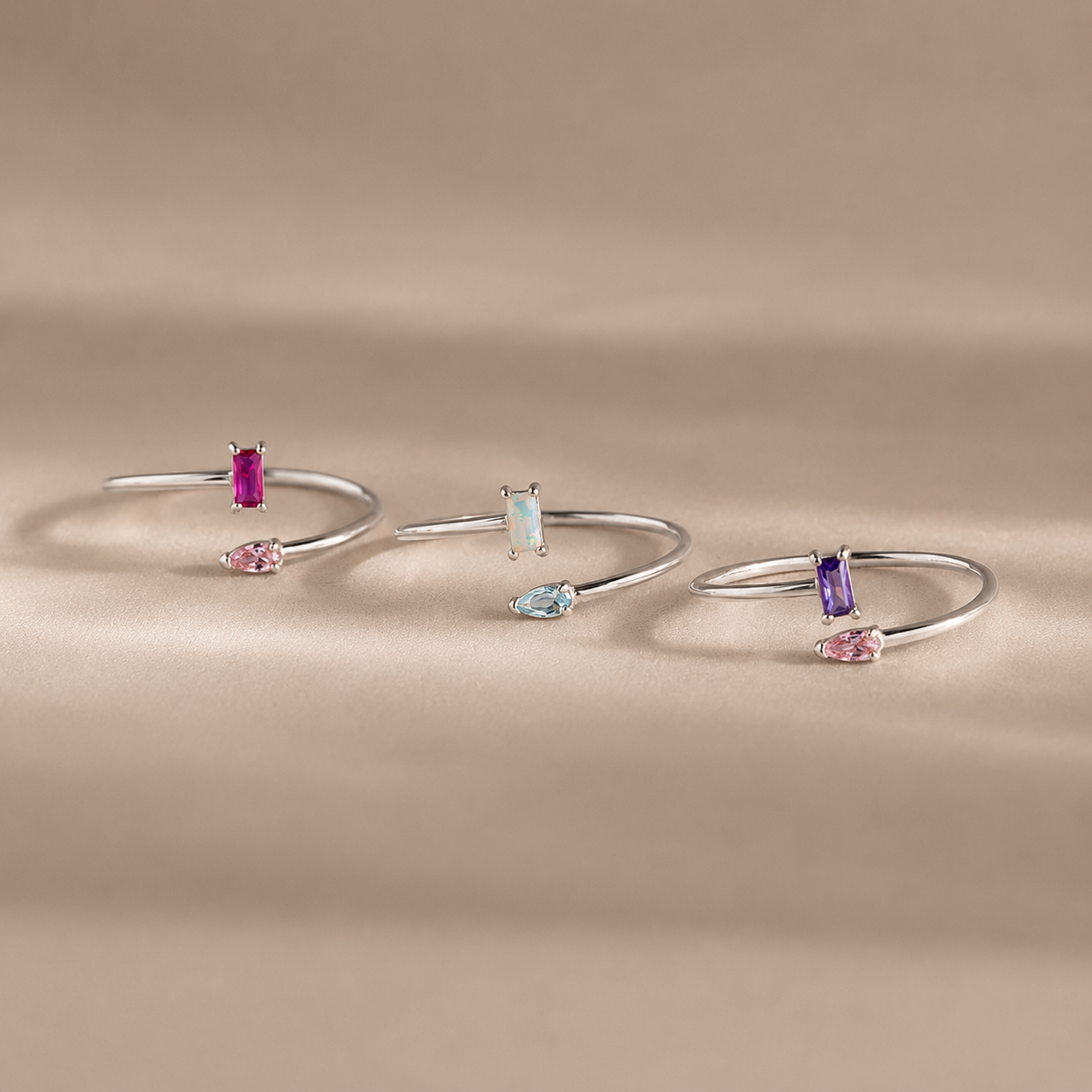 Set of silver bangle bracelets with gemstones on a beige background